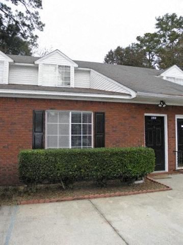 a brick house with a hedge in front of it