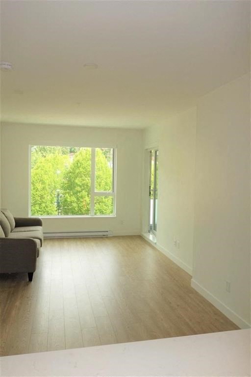 an empty living room with a large window and wooden floors