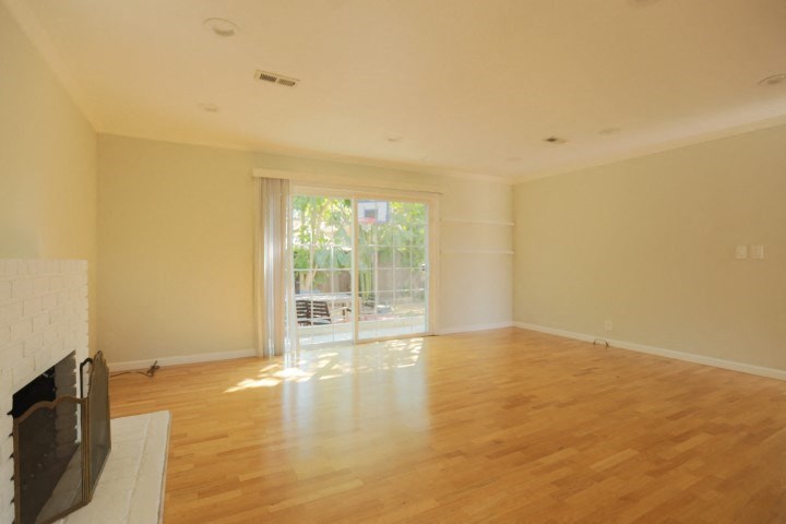 an empty living room with a fireplace and a sliding glass door