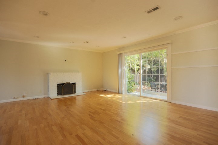 an empty living room with a fireplace and a sliding glass door