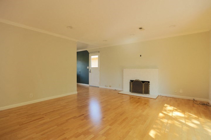an empty living room with a fireplace and wooden floors