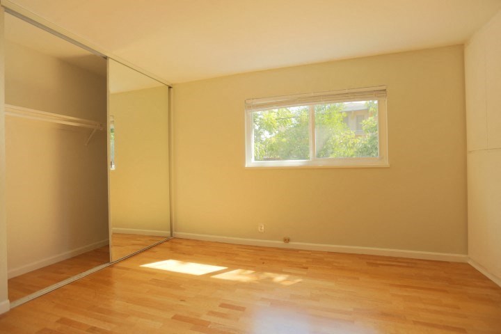 an empty room with a window and wooden floors