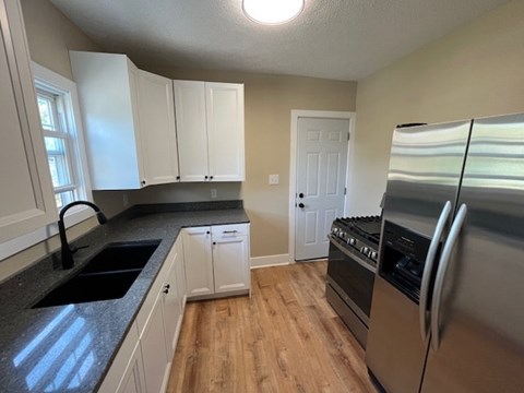 A kitchen with white cabinets and a stainless steel refrigerator.
