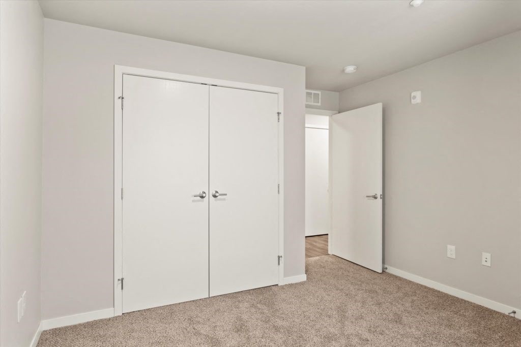 a bedroom with white closets and a carpeted floor
