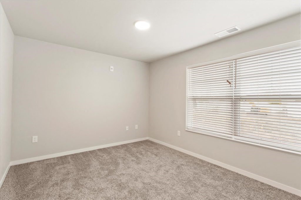 a bedroom with a large window and a carpeted floor