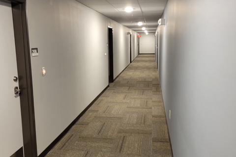 a hallway in a building with white walls and wood flooring