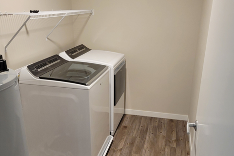 a washer and dryer in the corner of a room with a wood floor