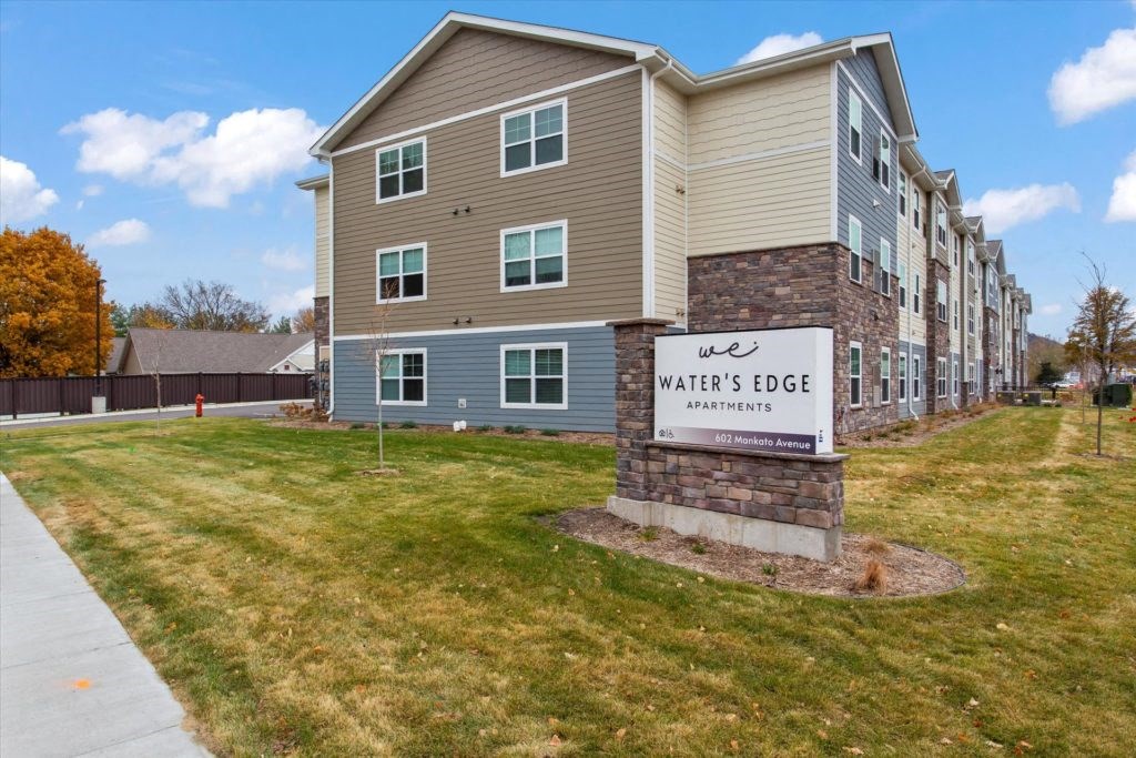 an apartment building with a sign that says waters edge and a sidewalk