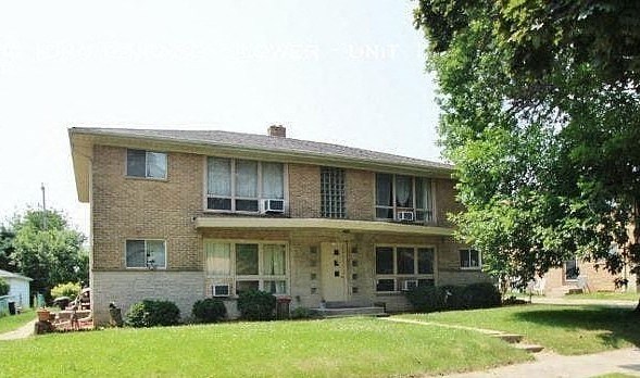 A two-story house with a front porch and a tree in the front yard.
