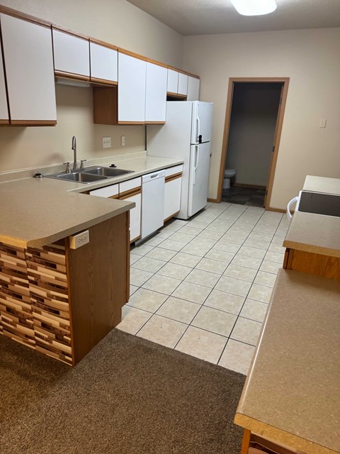A kitchen with white cabinets and a white refrigerator.