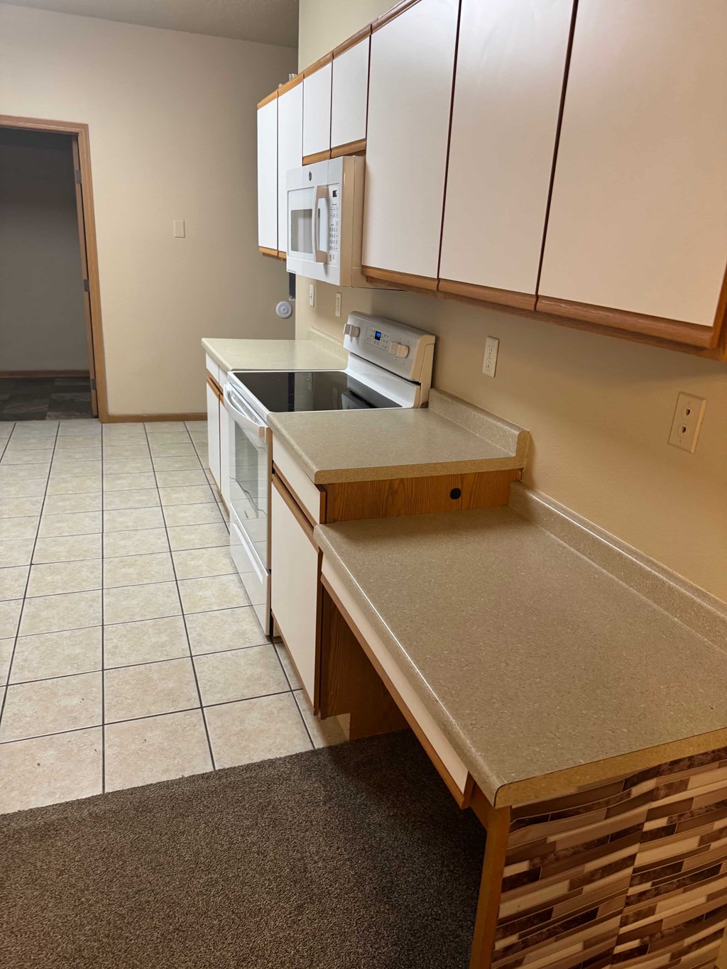A kitchen with white cabinets and a countertop with a sink and toaster oven.