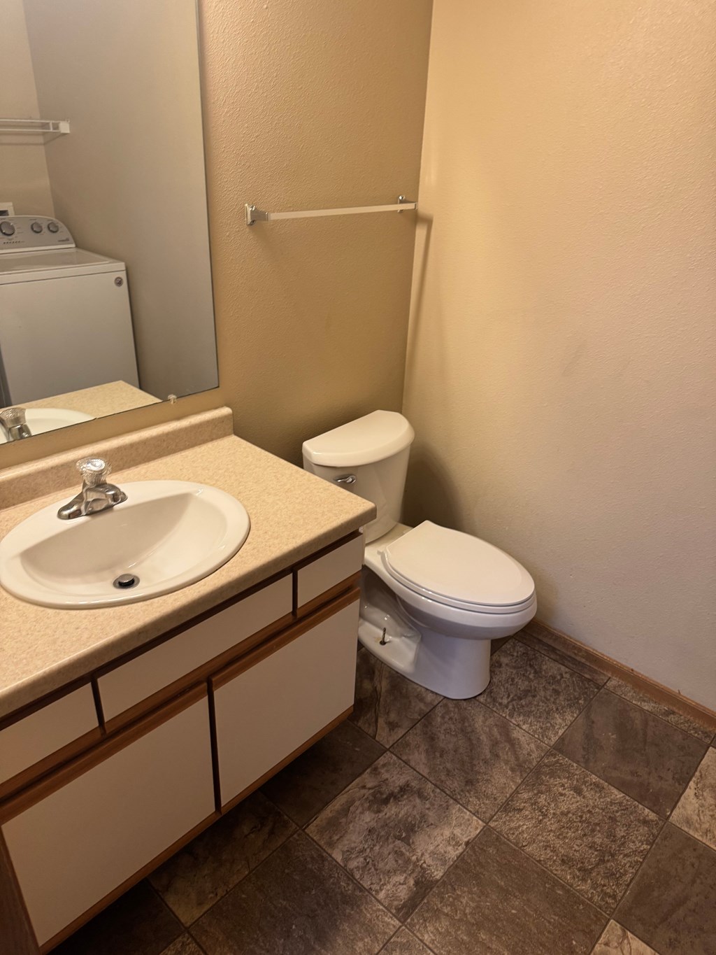 A bathroom with a toilet, sink, and tiled floor.