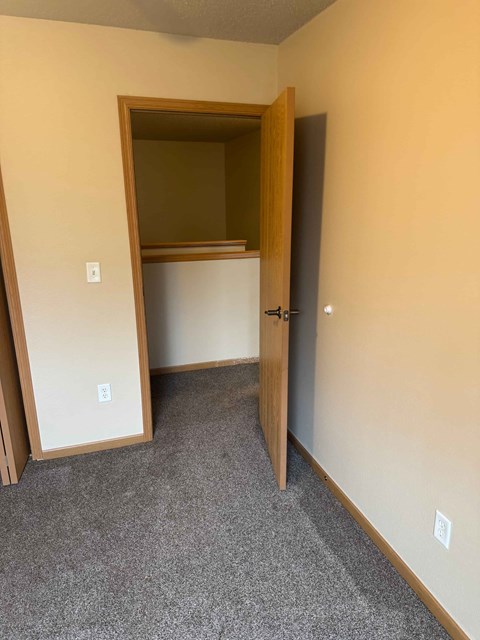 A room with a carpeted floor and a doorway leading to another room.