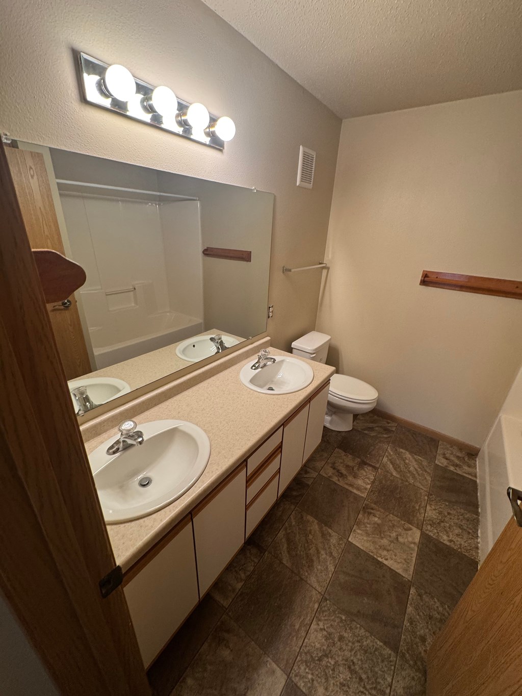 A bathroom with a brown tile floor and a mirrored medicine cabinet.