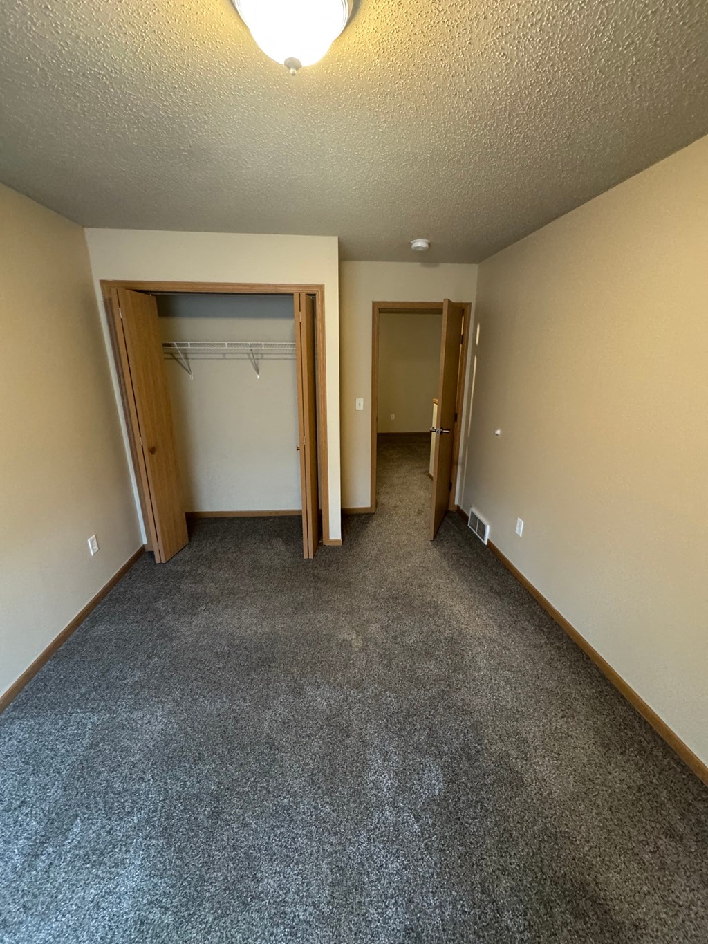 A room with a grey carpet and two doors.