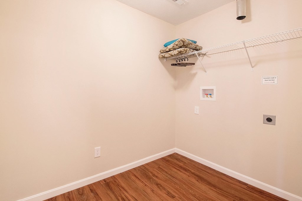 a room with a wooden floor and a white wall with a closet and a rack