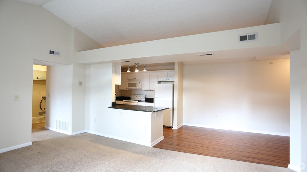 an empty living room with a kitchen in it