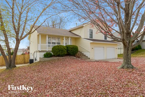 a yellow house with a yard with red leaves on the ground