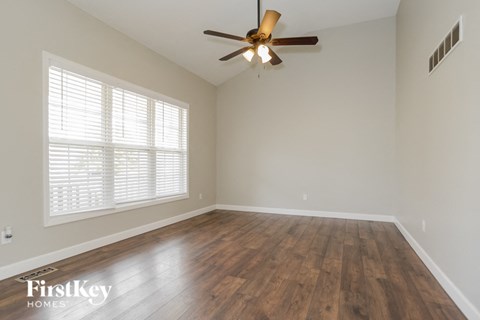 an empty living room with wood floors and a ceiling fan