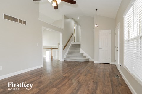 an empty living room with a staircase and a ceiling fan