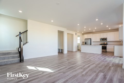 A spacious living room with a staircase and a kitchen area.