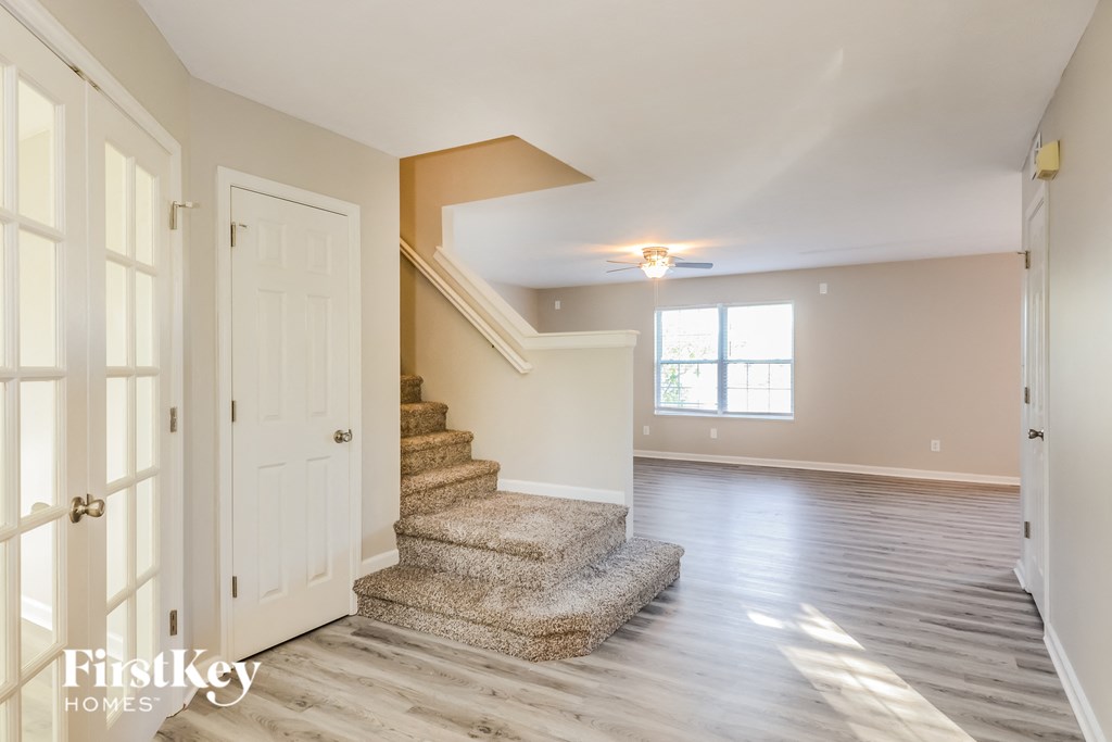 an empty living room with a staircase and a white door