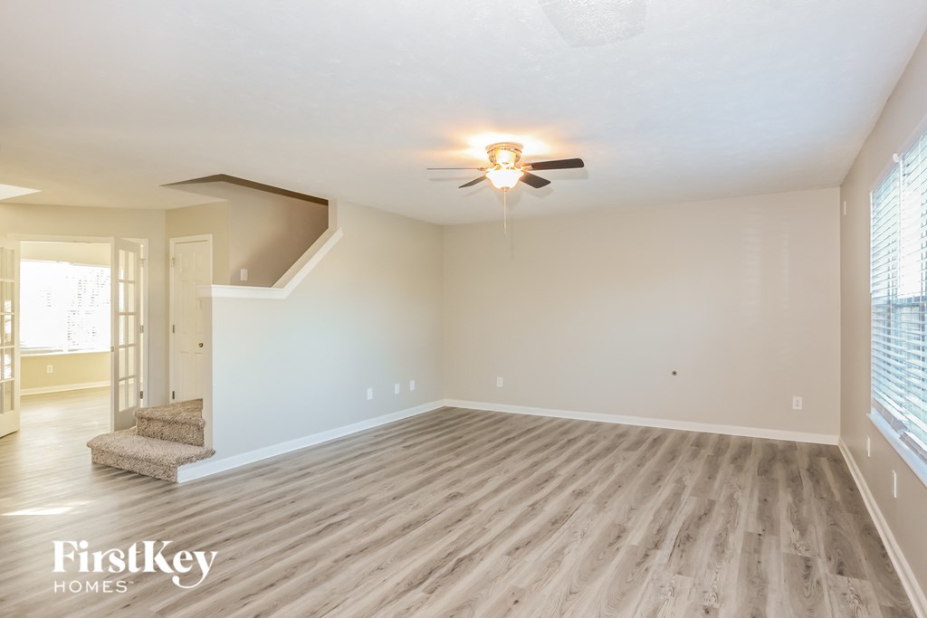 the living room of an empty house with a ceiling fan