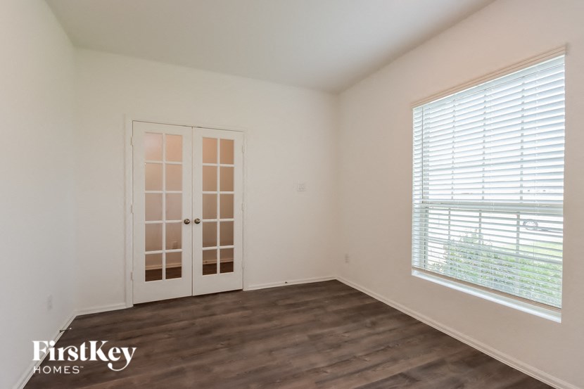 a bedroom with white walls and wood floors and a window