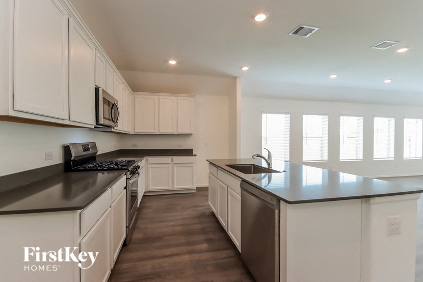a kitchen with white cabinets and black counter tops and stainless steel appliances