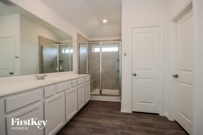 a bathroom with white cabinets and a large mirror and a shower