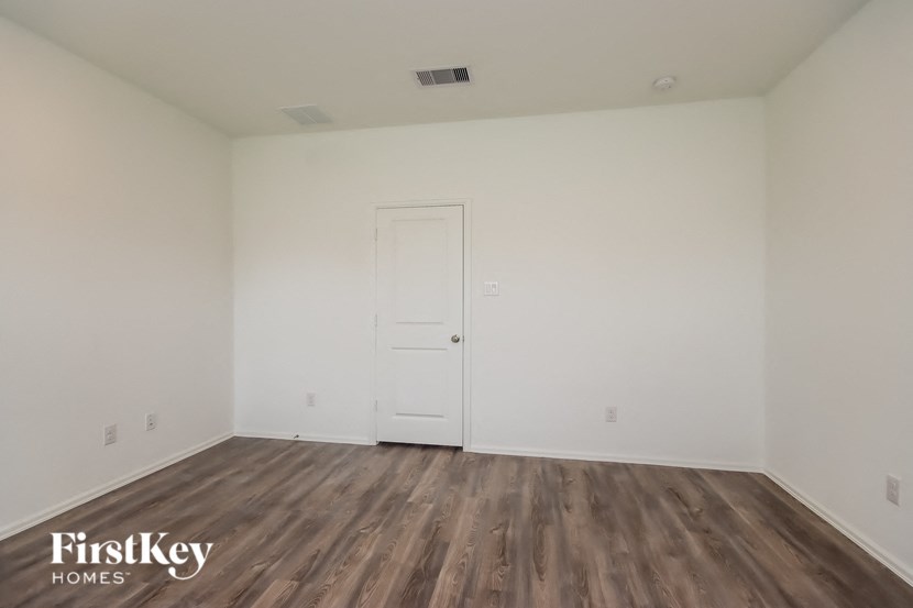a bedroom with white walls and wood flooring and a door