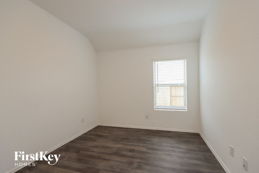 a bedroom with white walls and a window and wooden floors