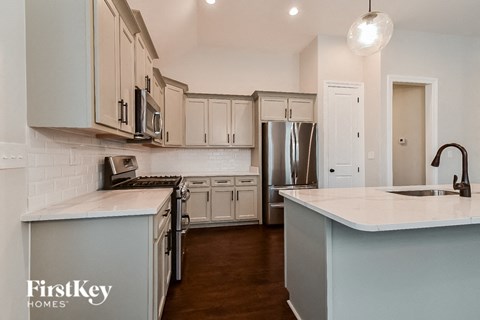 A kitchen with a white counter top and a stainless steel refrigerator.