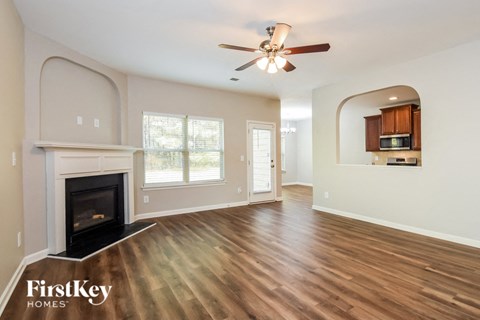 an empty living room with a fireplace and a ceiling fan