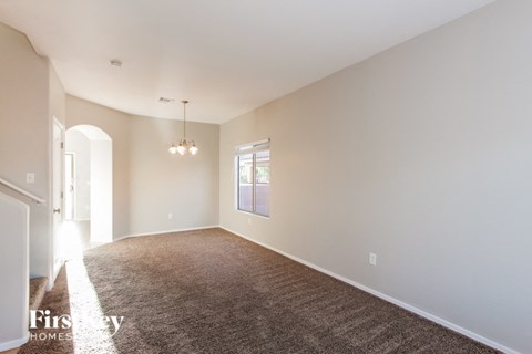 a spacious living room with carpet and white walls