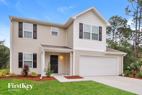 a beige house with black shutters and a driveway