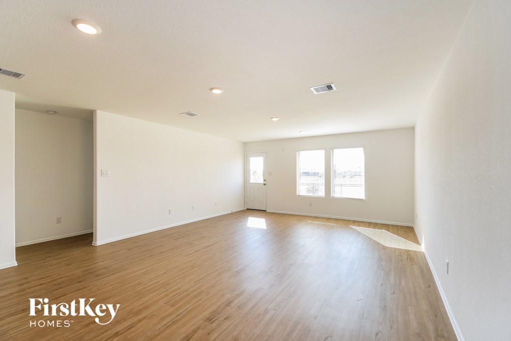 A spacious room with wooden floors and two windows.