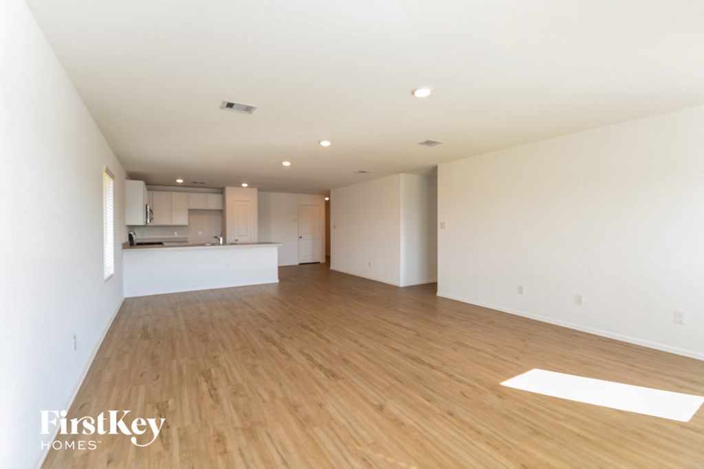 A spacious room with wooden flooring and a white mat on the floor.
