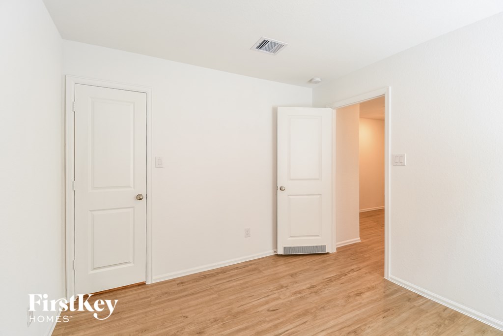 A room with two white doors and wooden floors.