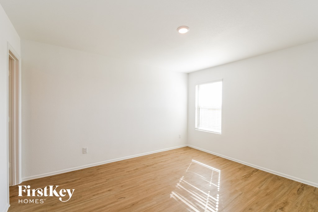 A room with wooden floors and a window letting in sunlight.