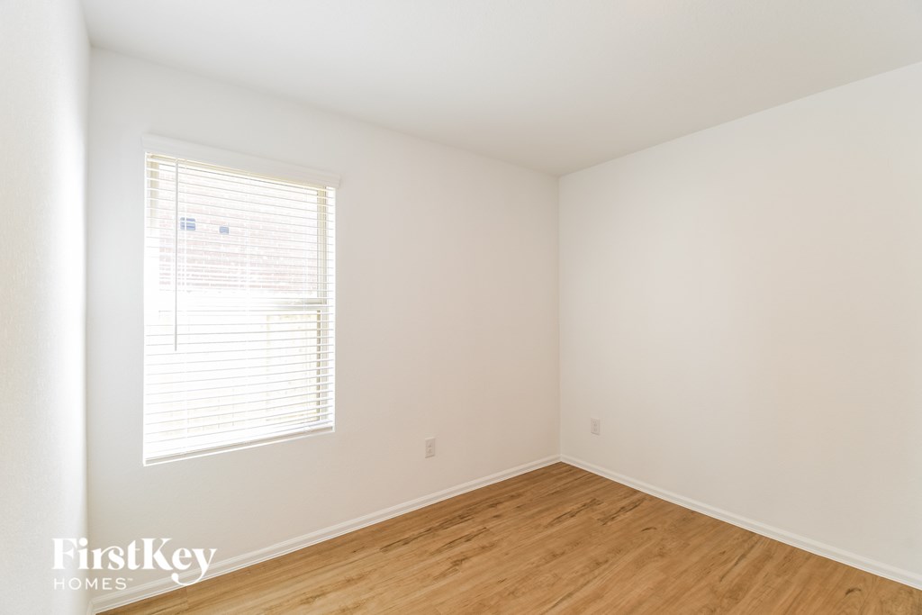A room with wooden flooring and a window with blinds.