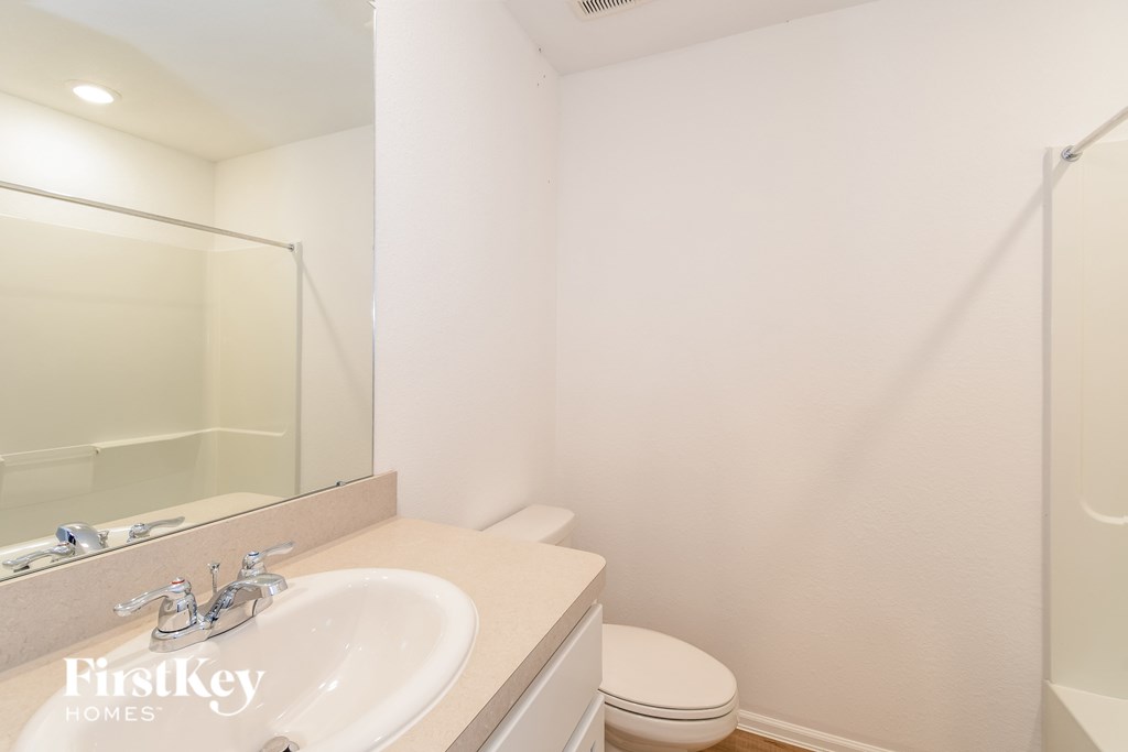 A bathroom with a sink, toilet, and mirror.
