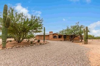 a house in the desert with a gravel driveway and cacti