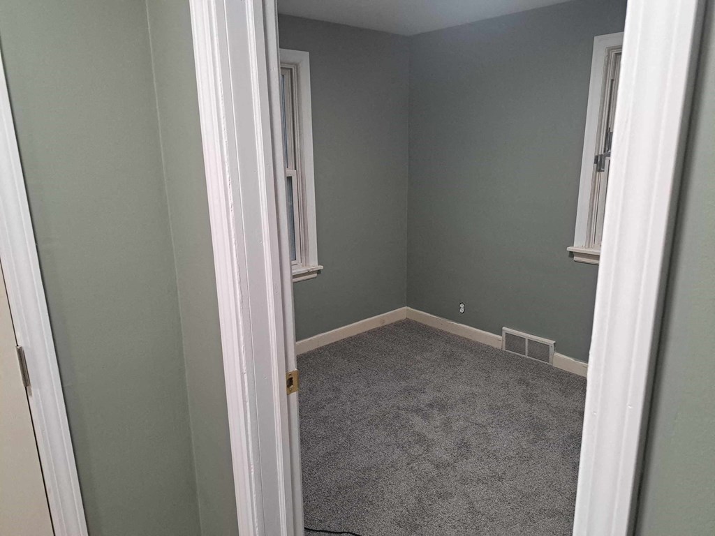 a small room with a carpeted floor and two windows