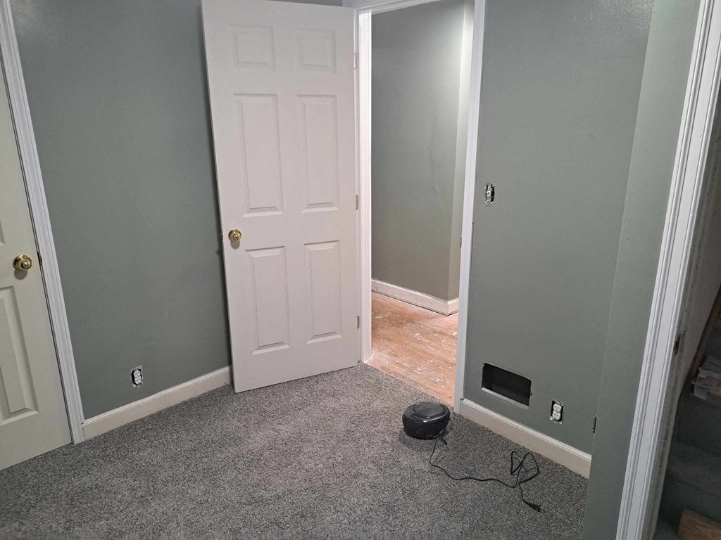 a room with a white door and a hallway with a dog bowl on the floor