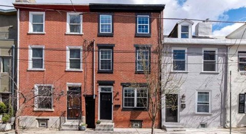 A red brick building with a black door in front.