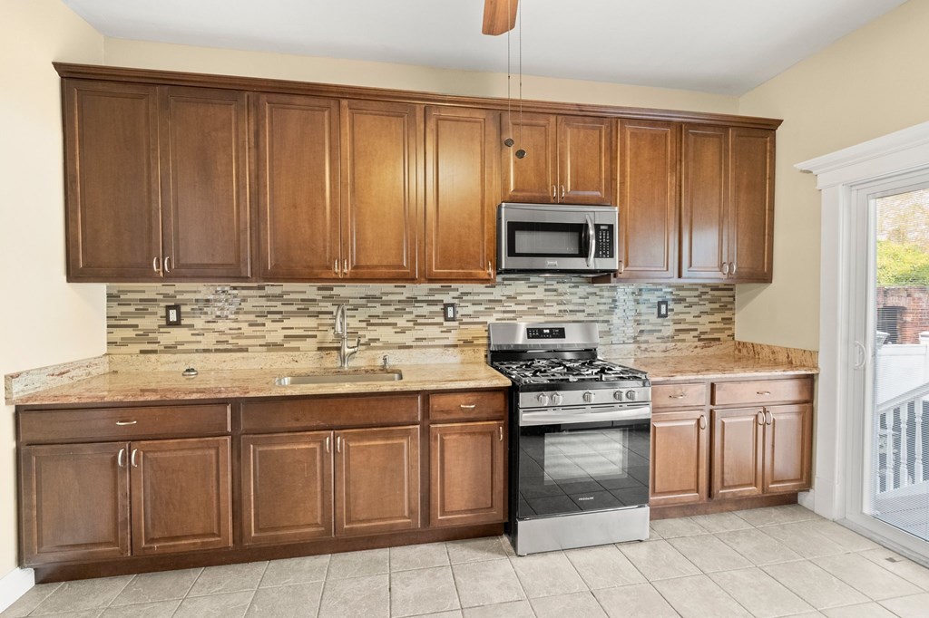 A kitchen with brown cabinets and a tiled backsplash.