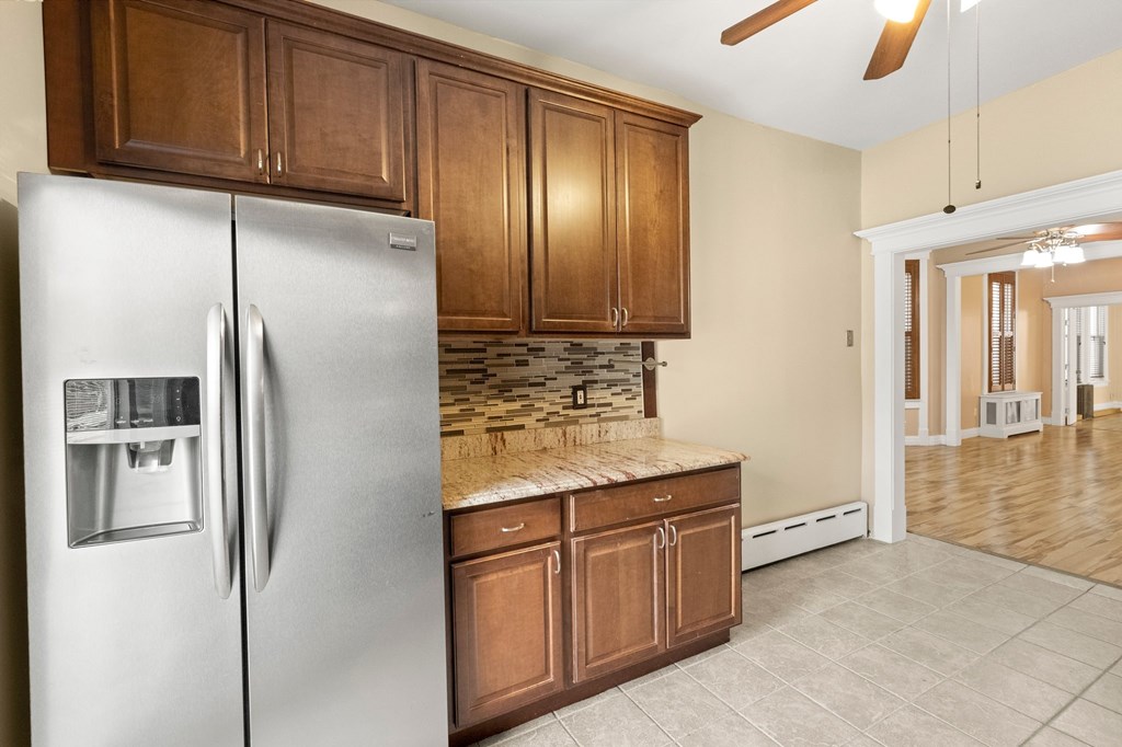 A kitchen with a refrigerator and wooden cabinets.