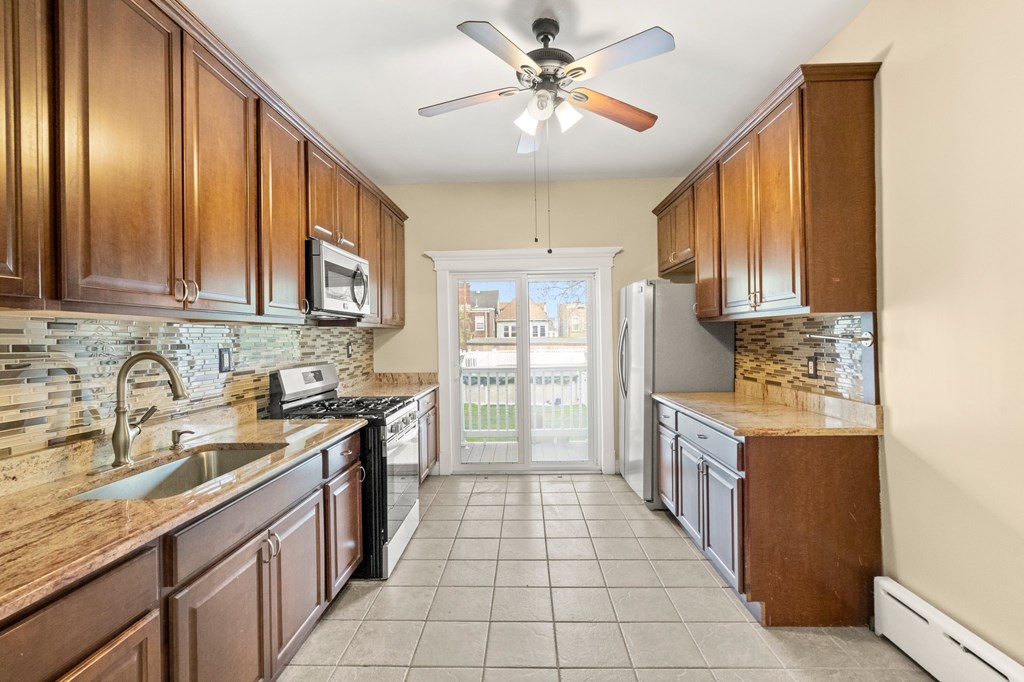 A kitchen with brown cabinets and a fan.