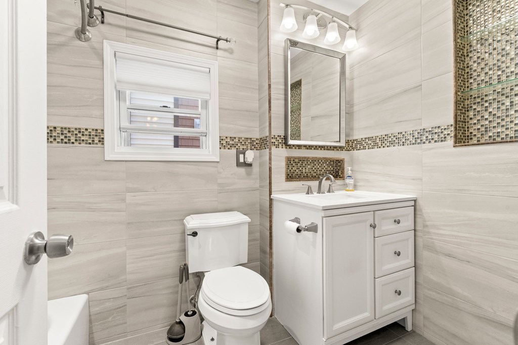 A white bathroom with a toilet, sink, and mirror.